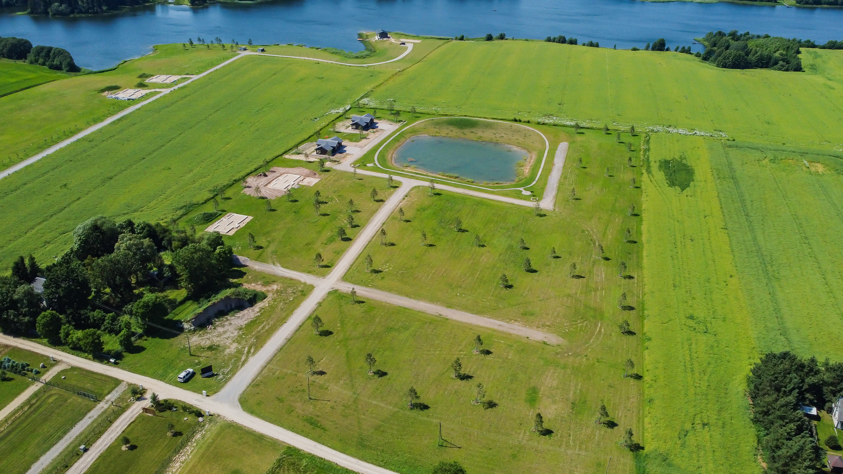 Sklypai tarp laukų, ežeras horizonte